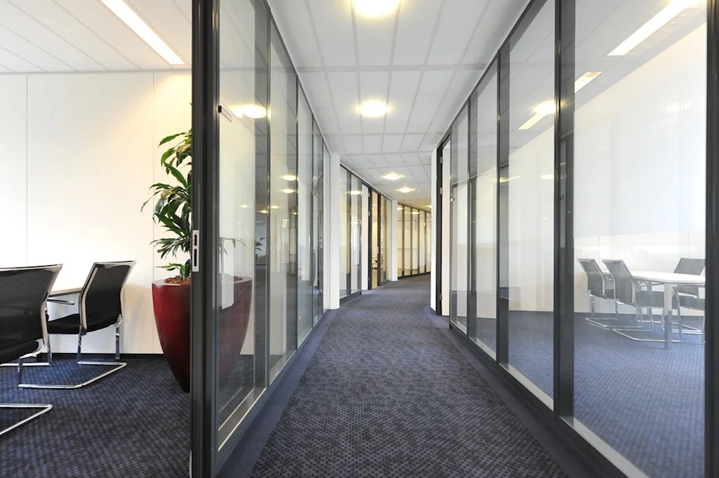 Moderne kantoorhal aan de Laan van s-Gravenmade met glazen wanden en vergaderruimtes.